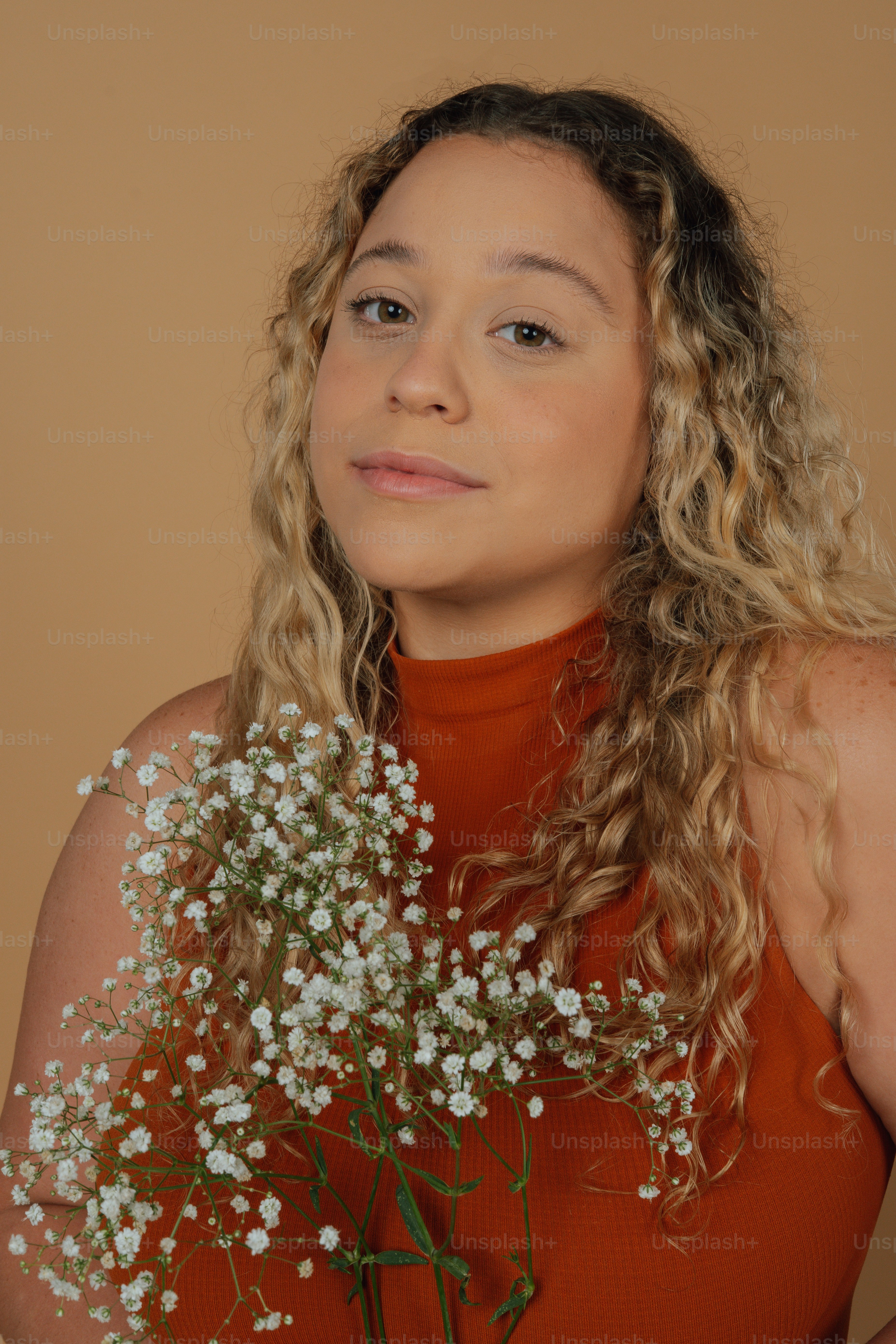 a woman with curly hair holding a bouquet of flowers