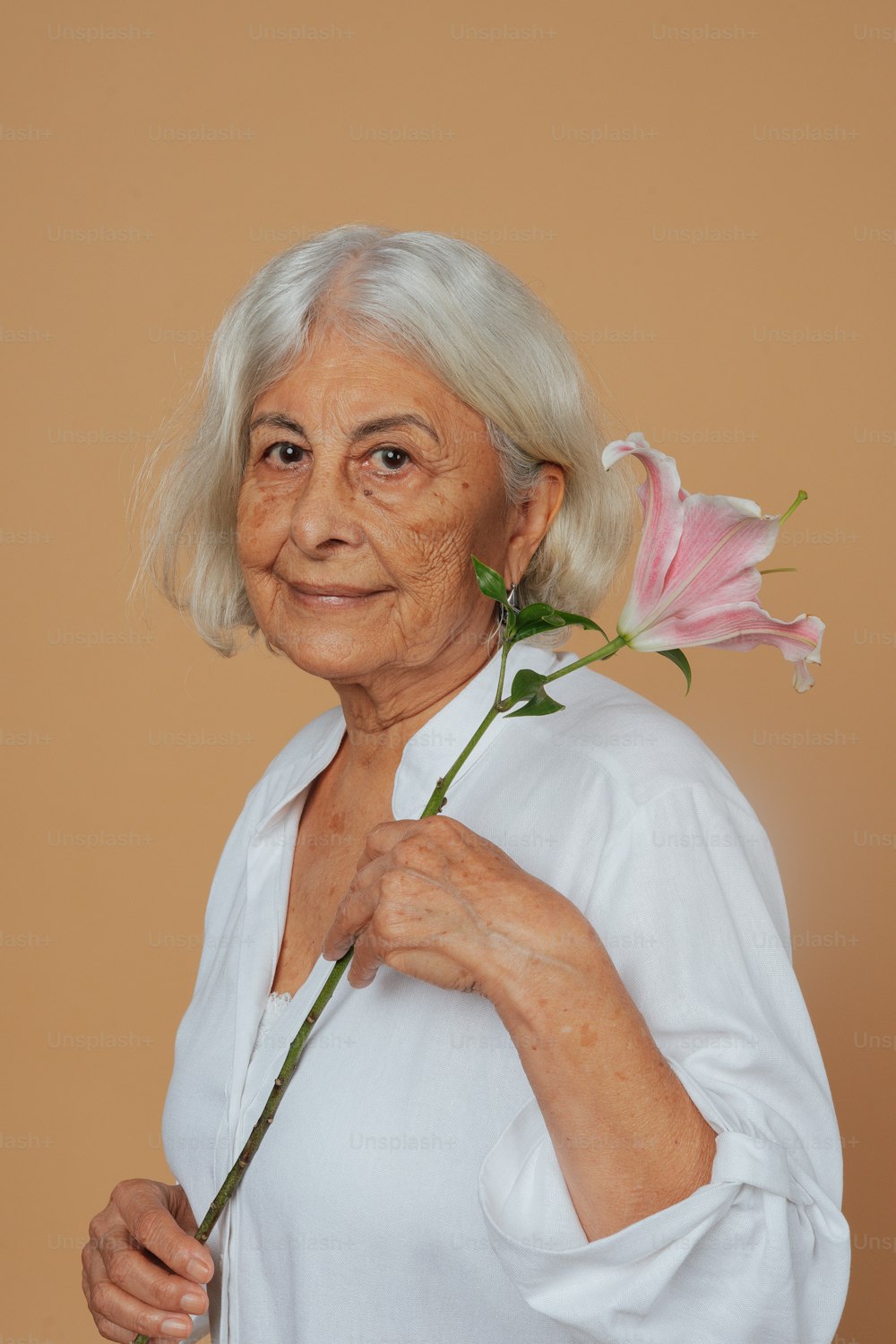 uma mulher mais velha segurando uma flor em sua mão