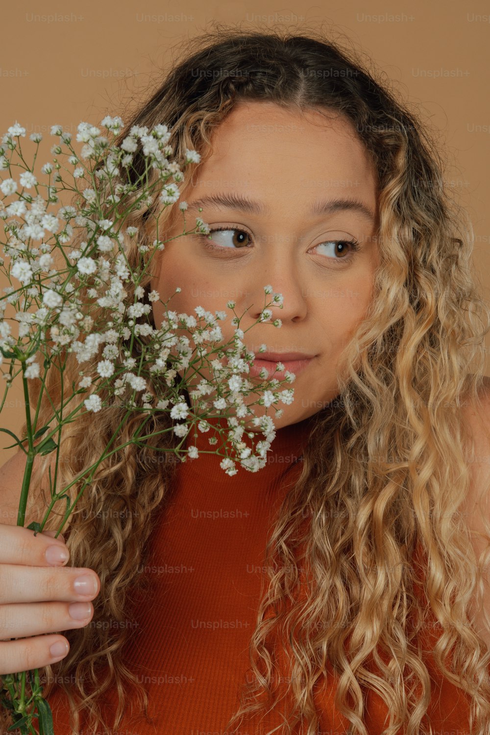 a woman with curly hair holding a bunch of flowers