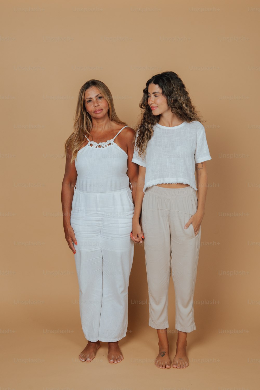 two women standing next to each other in white outfits