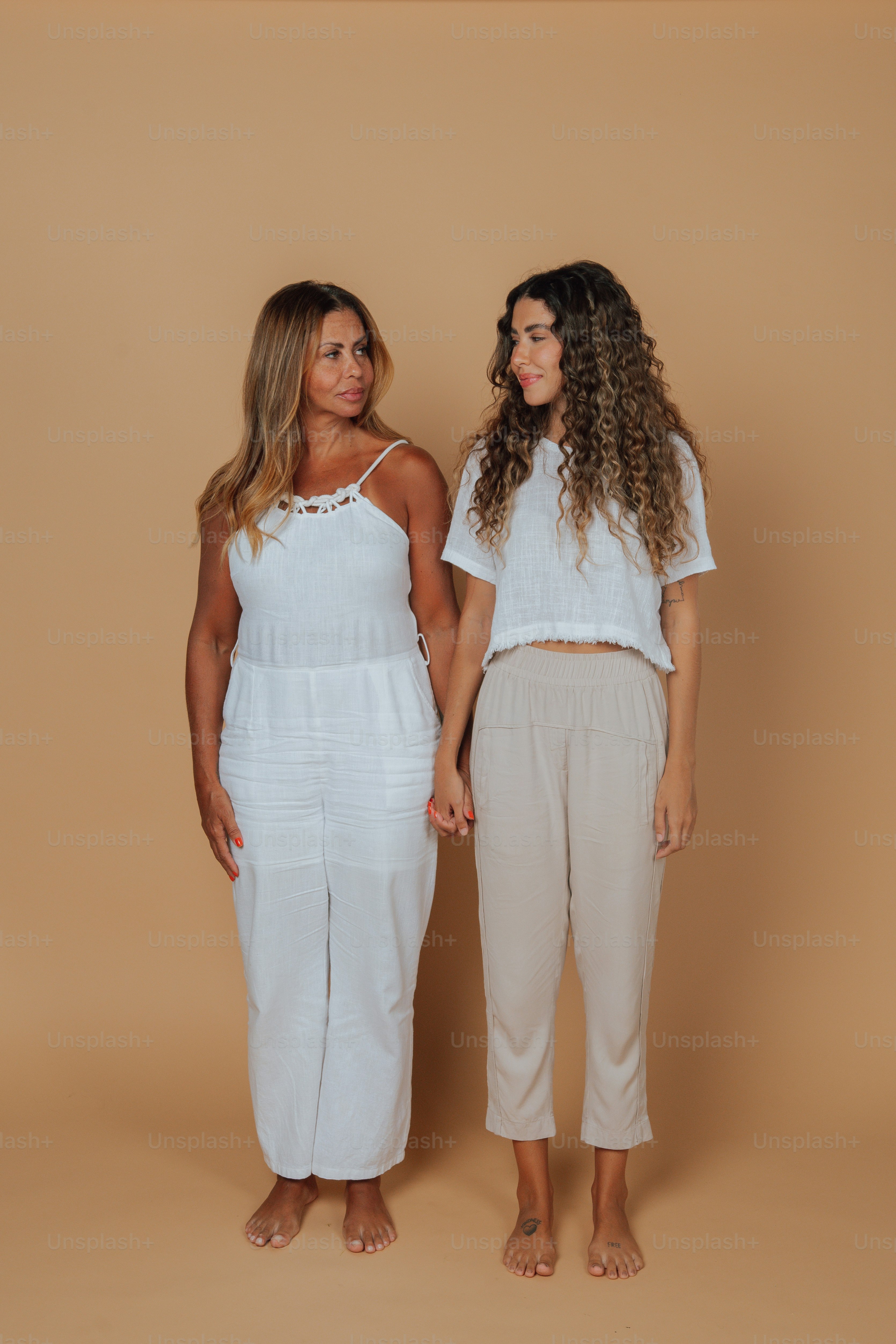 Due donne in piedi l'una accanto all'altra in abiti bianchi