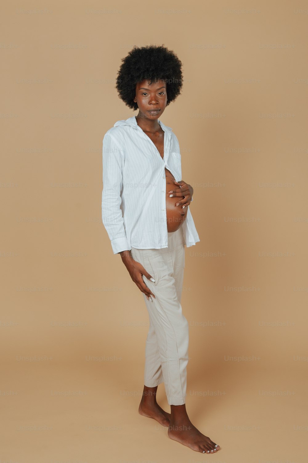 a woman with an afro standing in front of a tan background