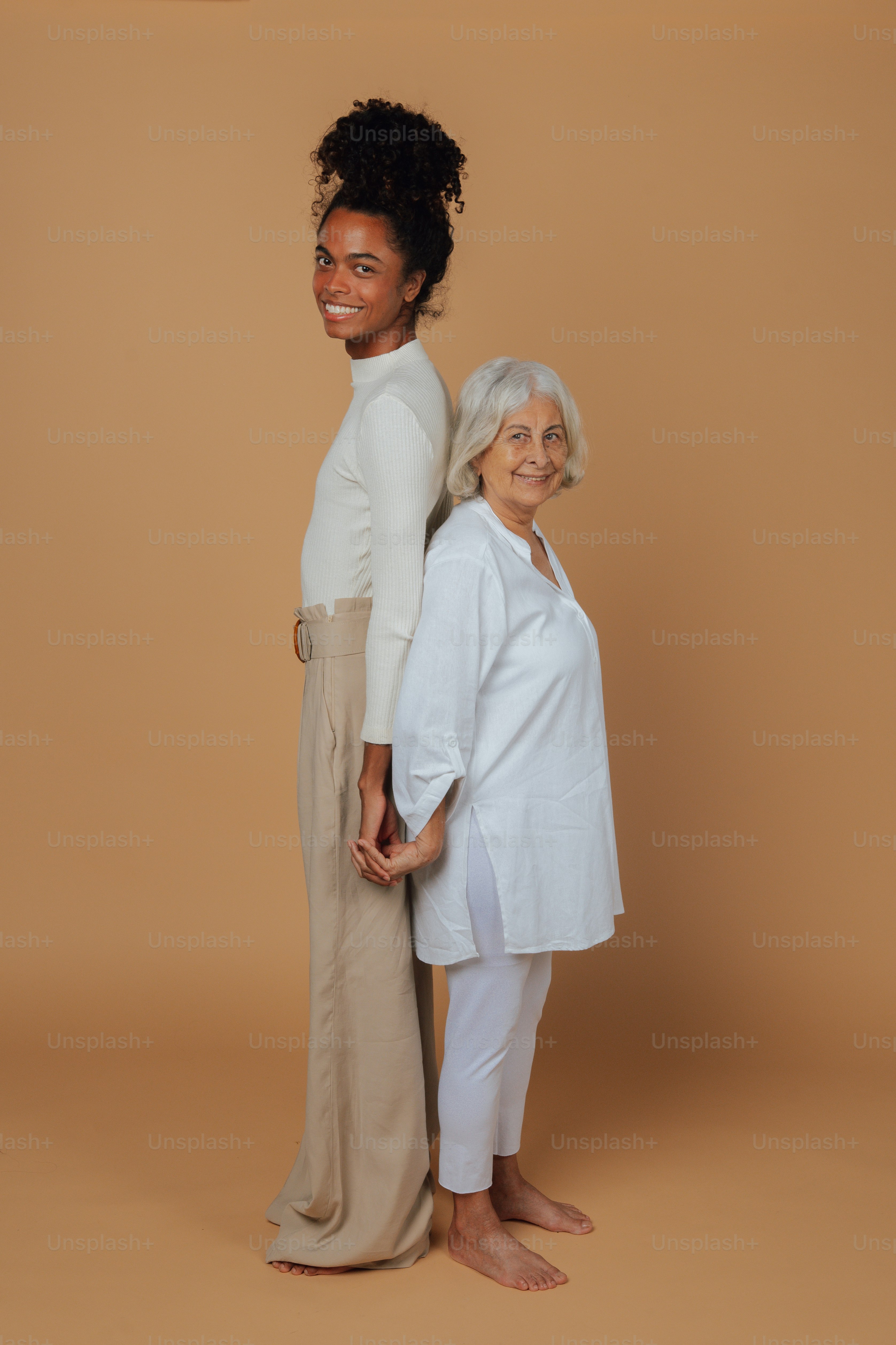 two women standing next to each other in front of a brown background