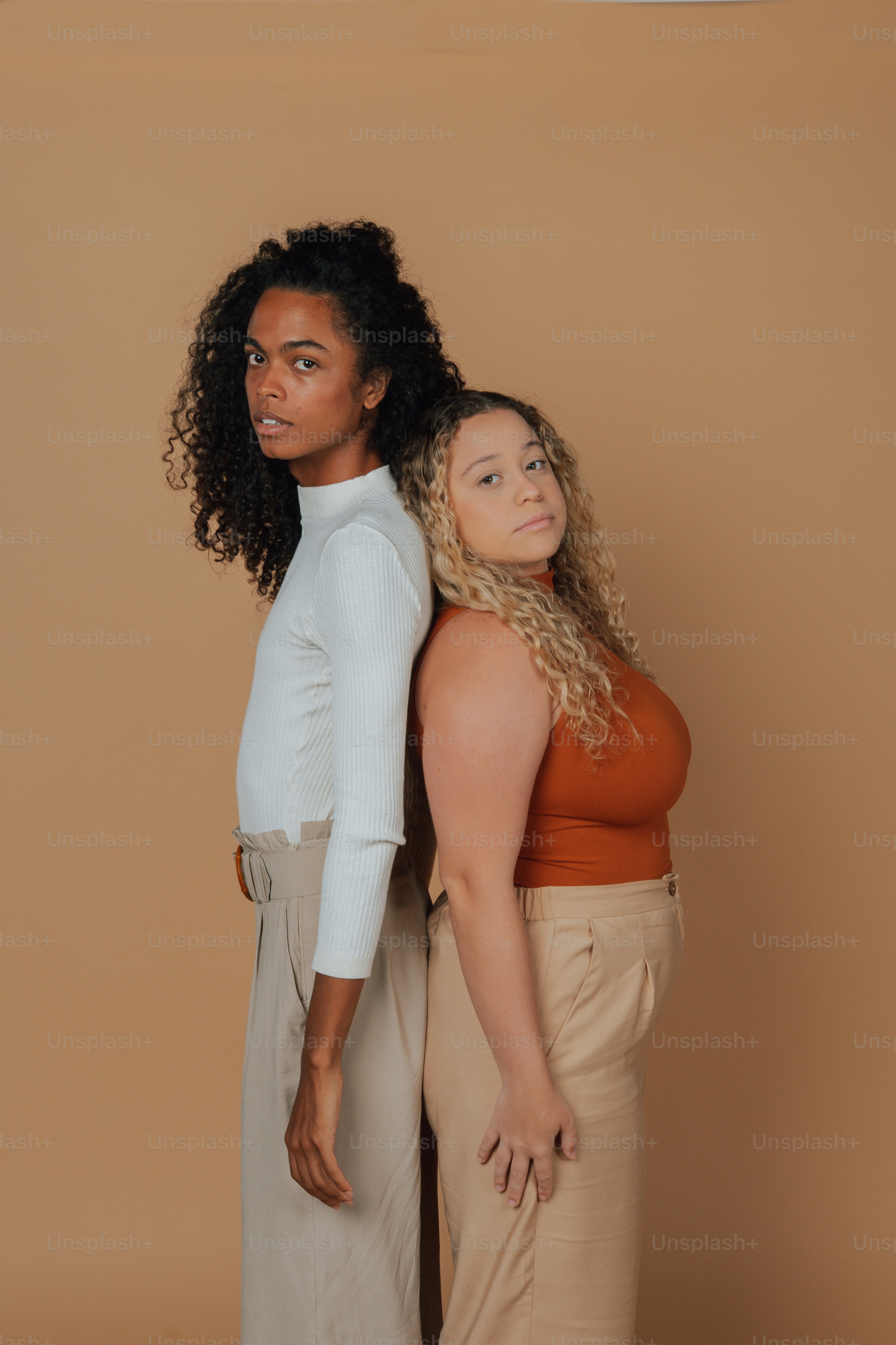two women standing next to each other in front of a wall