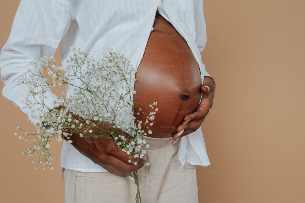 a pregnant woman holding a bouquet of baby's breath