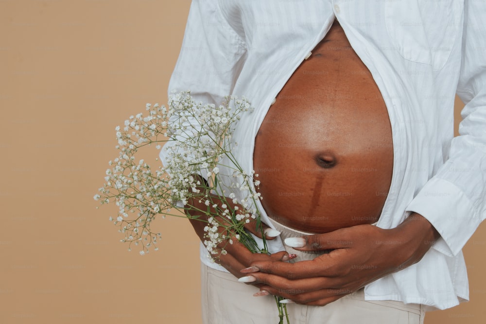 a pregnant woman holding a bouquet of flowers