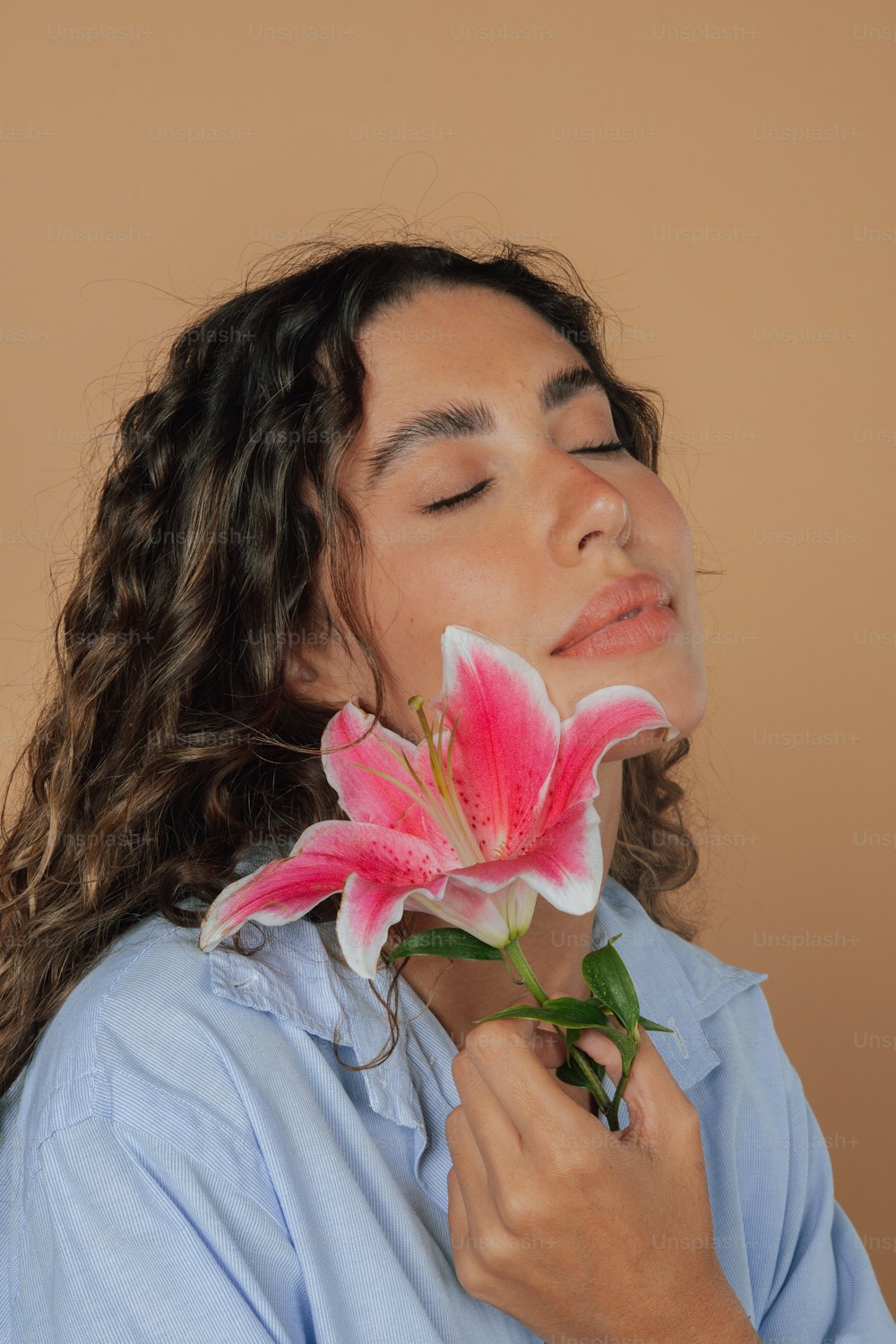 a woman is smelling a flower with her eyes closed