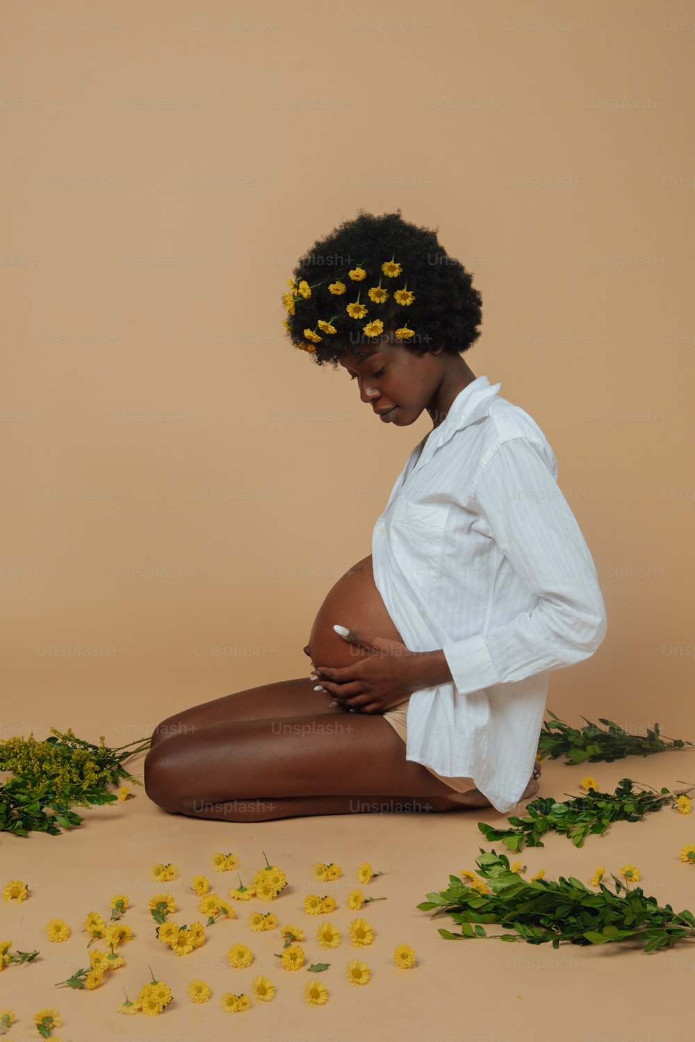 a woman sitting on the ground surrounded by flowers