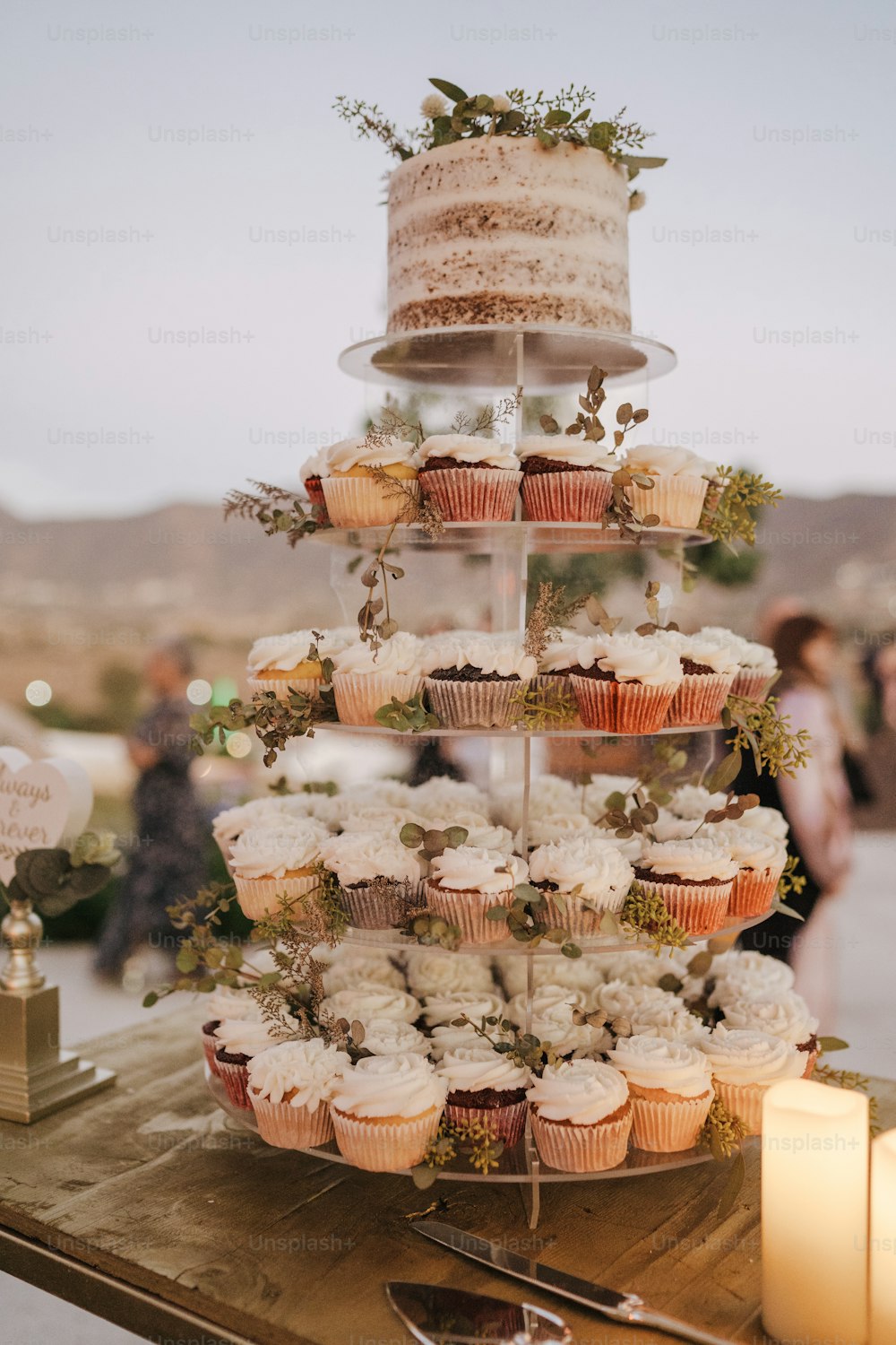 un gâteau à plusieurs niveaux avec des cupcakes et de la verdure dessus