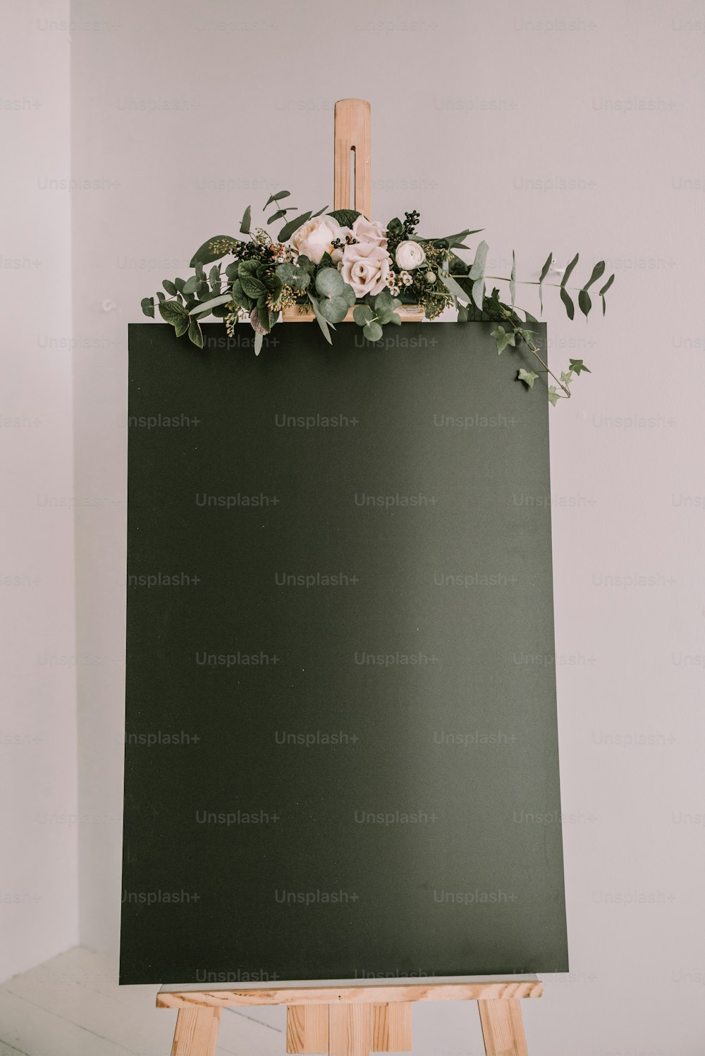 an easel with flowers and greenery on top of it