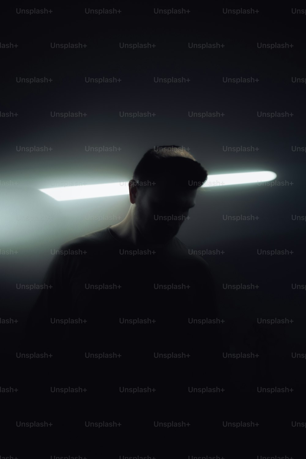 Un uomo in piedi in una stanza buia sotto una luce