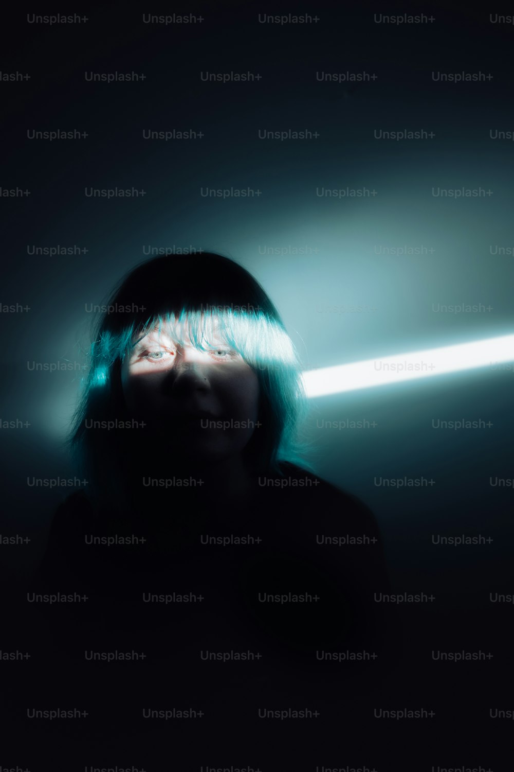 uma mulher em um quarto escuro com uma luz que vem através de seus olhos