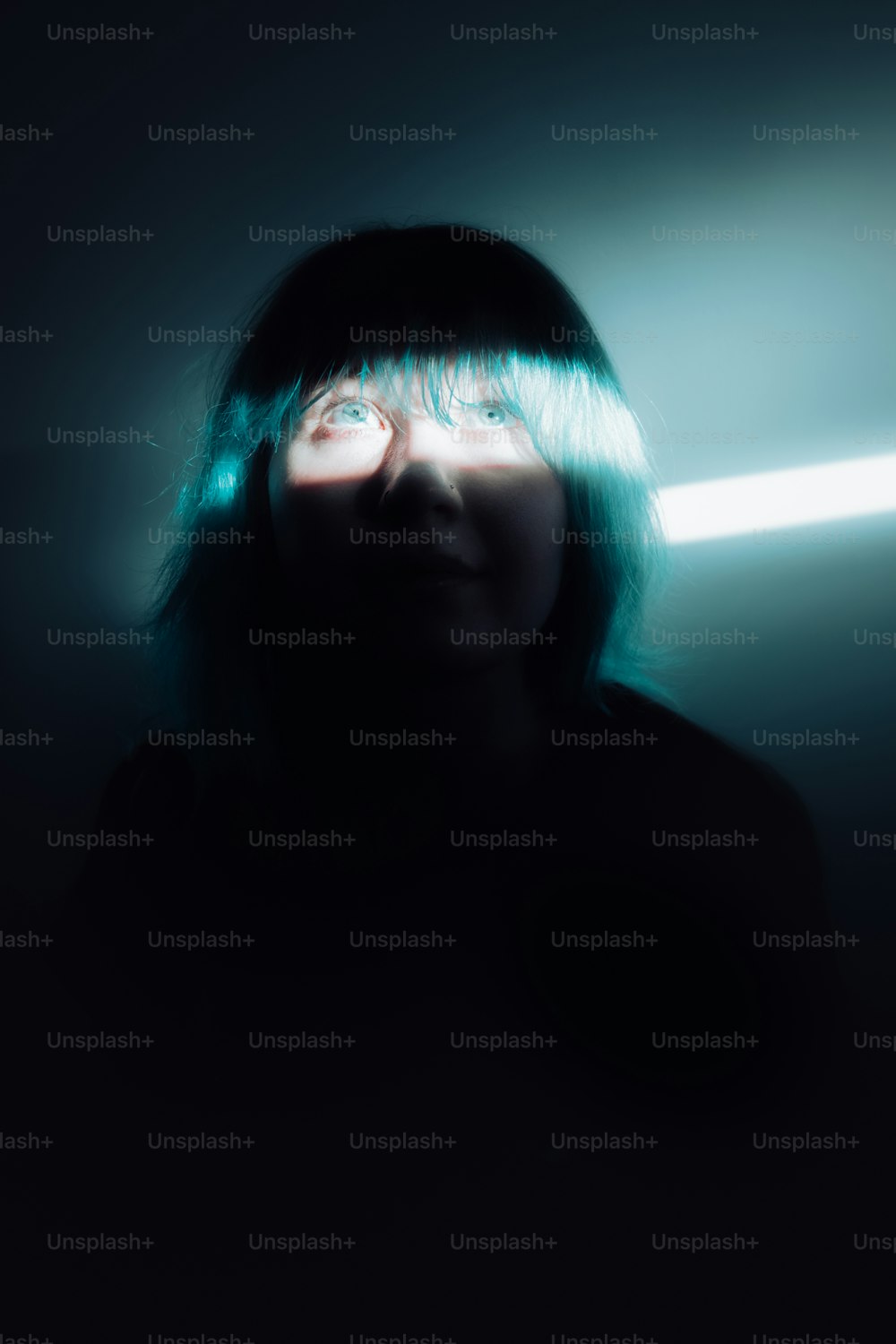 Una mujer en una habitación oscura con una luz entrando por sus ojos