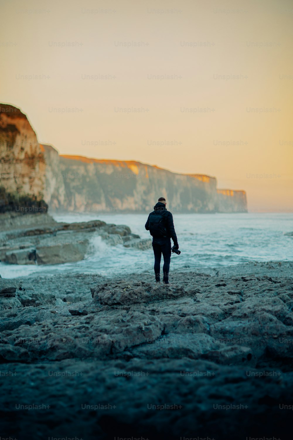 Un hombre caminando por una playa rocosa junto al océano