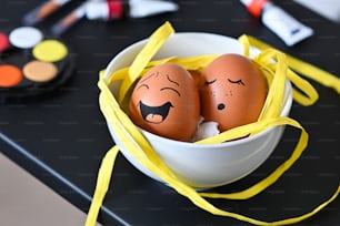 Dos huevos con caras pintadas en un tazón