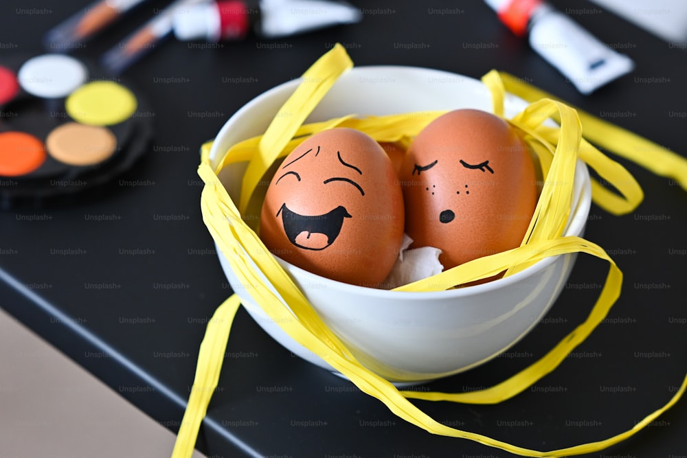 two eggs with faces painted on them in a bowl