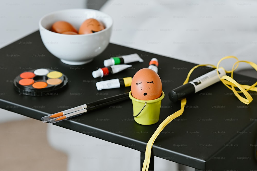 una mesa cubierta con un tazón de huevos y marcadores