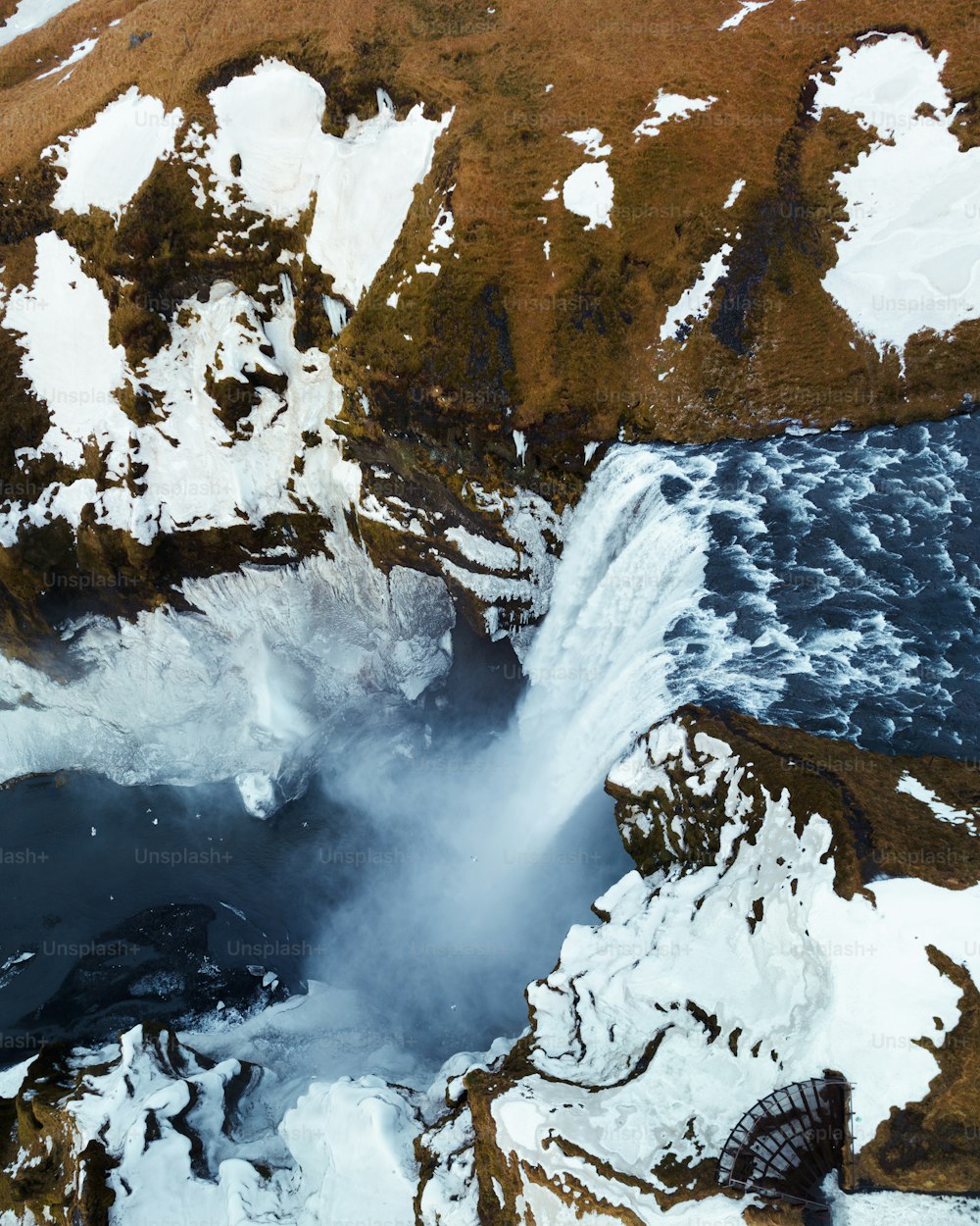 an aerial view of a waterfall surrounded by snow