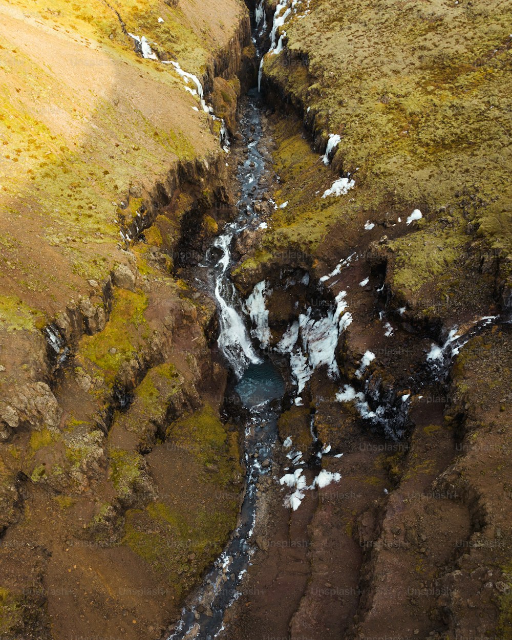 an aerial view of a stream running through a valley