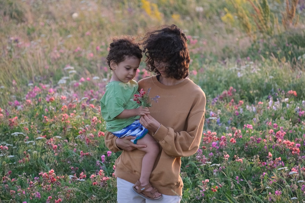 a woman holding a child in a field of flowers