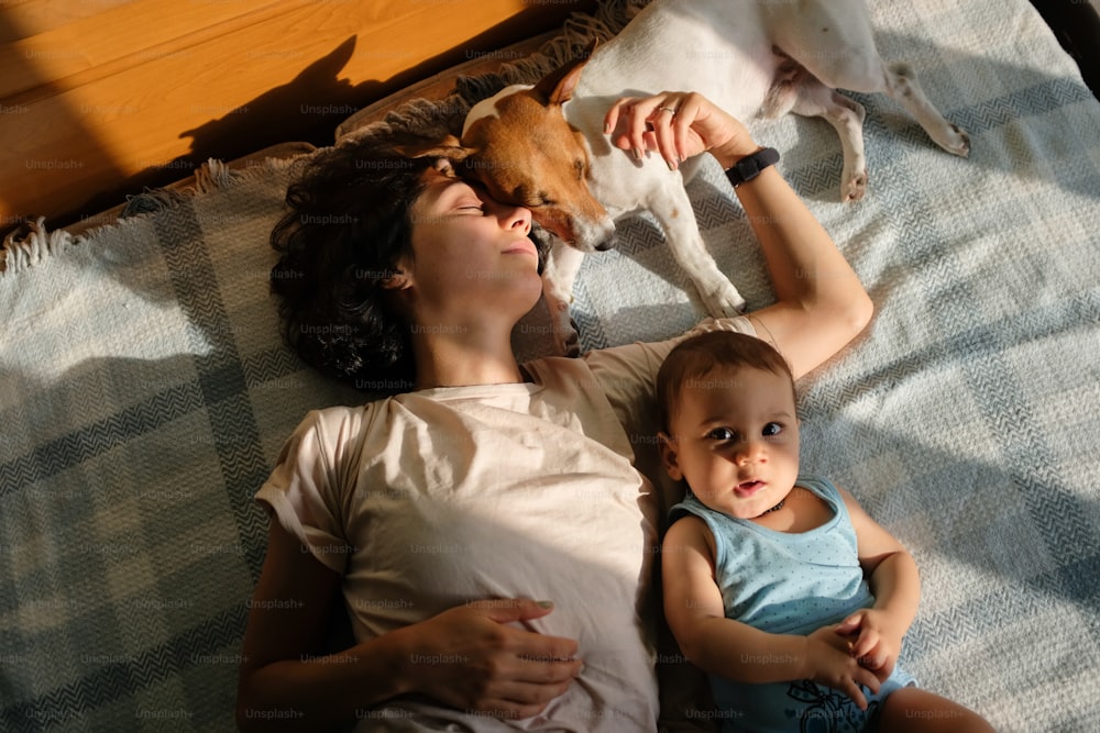 a woman laying in bed with a baby and a dog