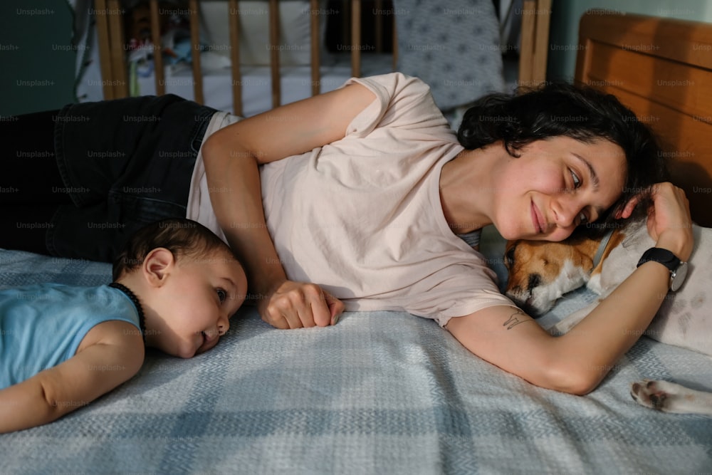 Eine Frau liegt auf einem Bett neben einem Baby und einem Hund