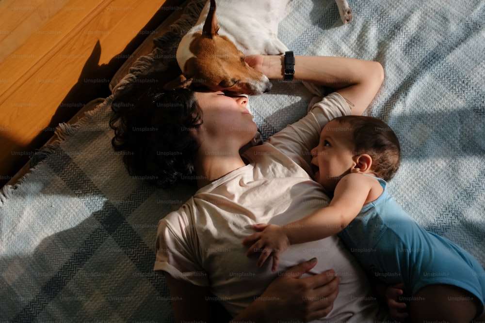 a woman laying on a bed with a baby and a dog
