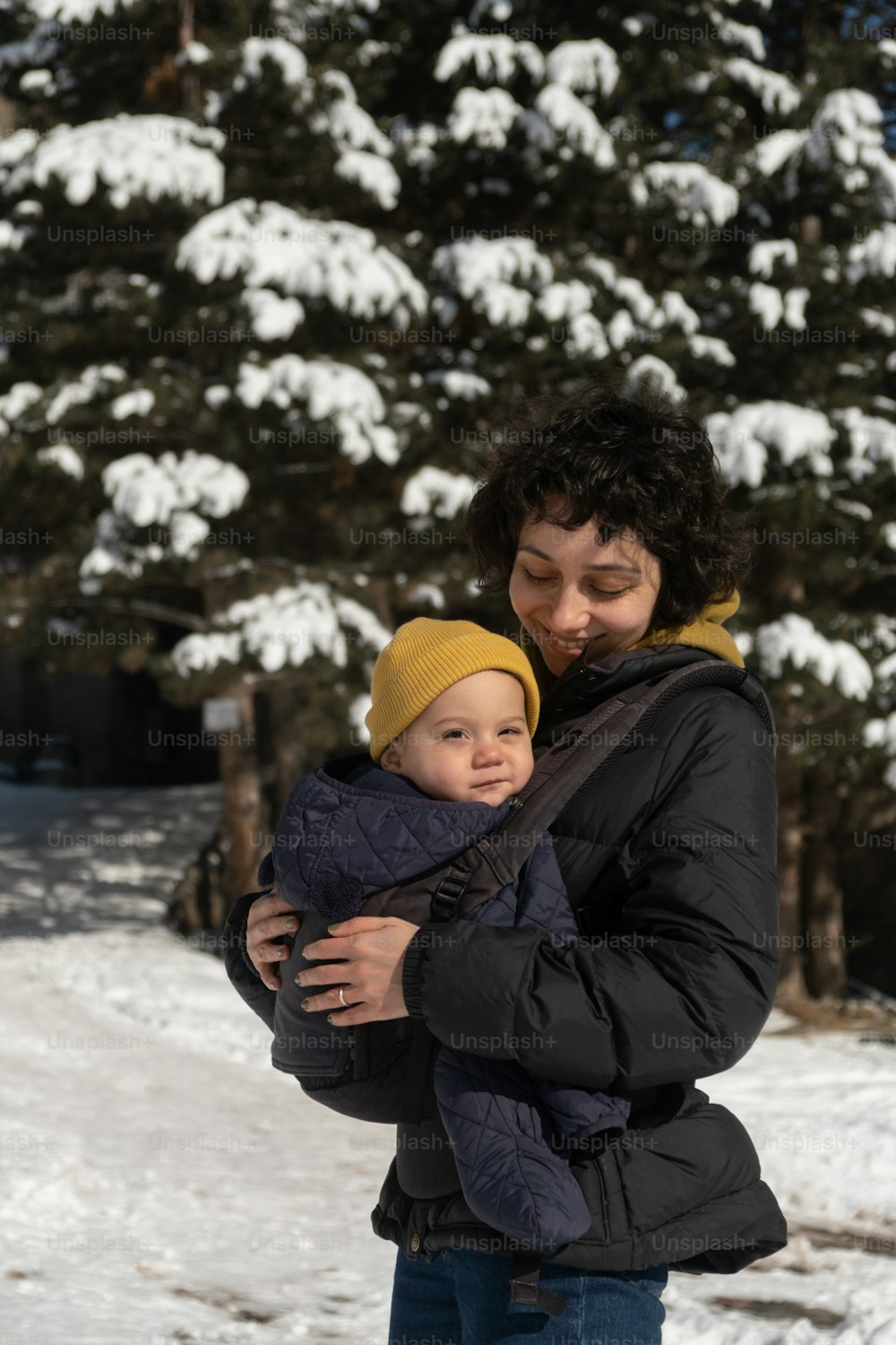 uma mulher segurando uma criança em seus braços na neve