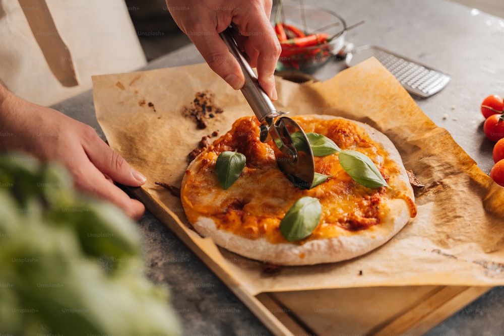 a person cutting a pizza on a cutting board