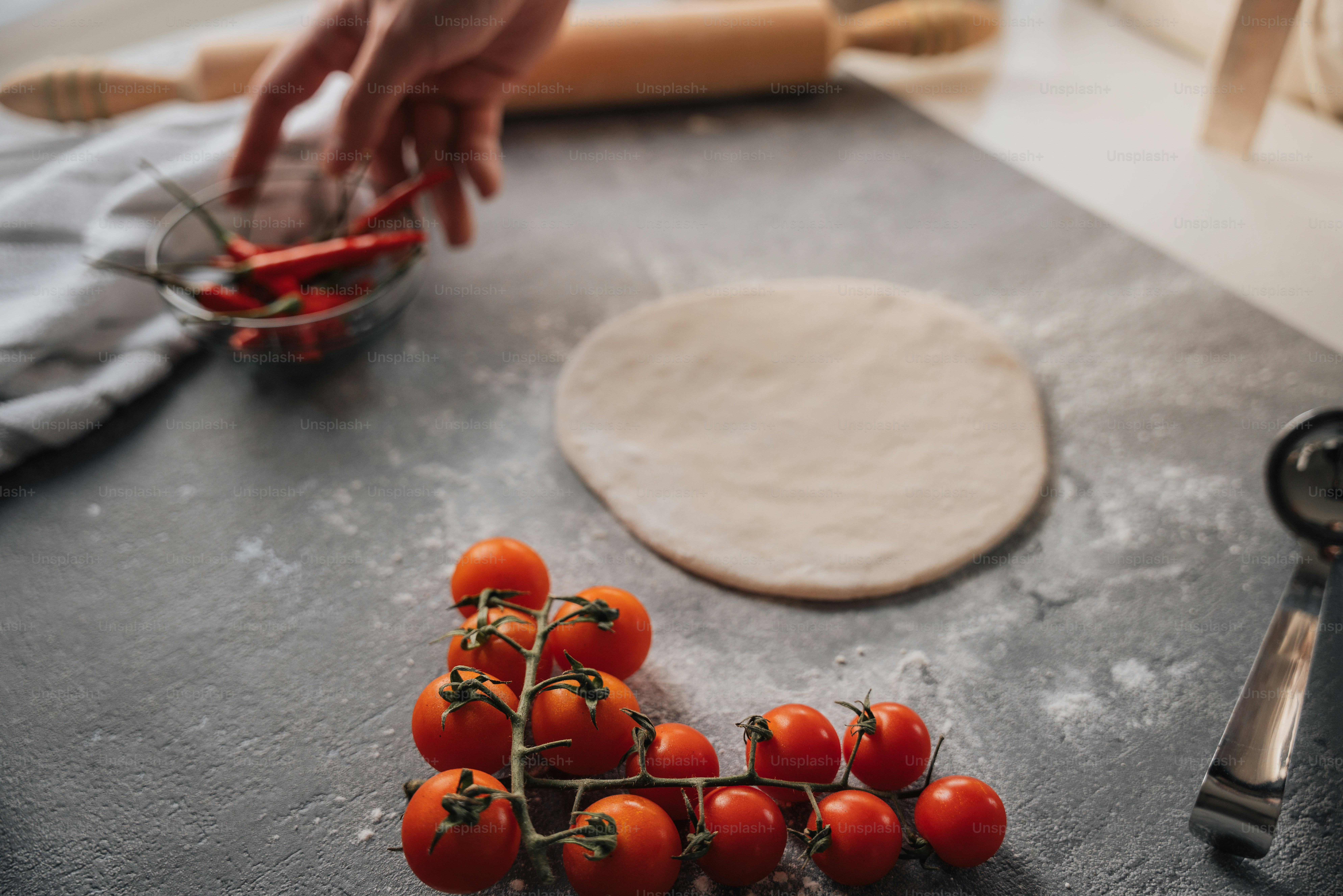 a bunch of tomatoes sitting on a counter next to a pizza cutter