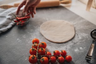 a bunch of tomatoes sitting on a counter next to a pizza cutter