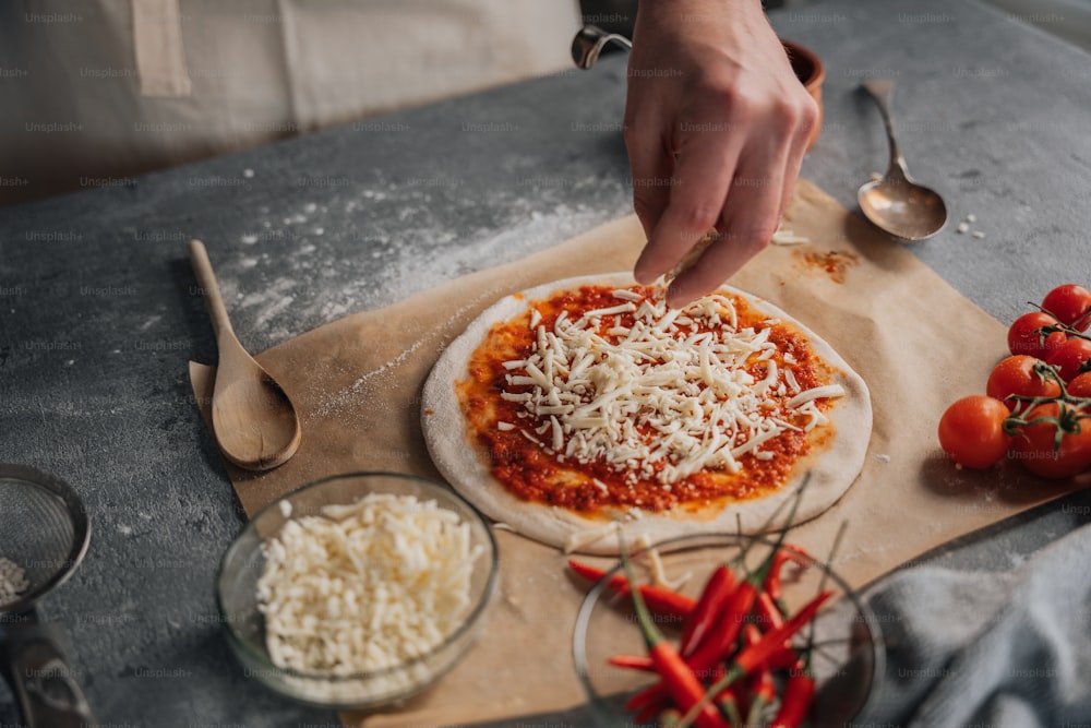 a person putting cheese on a pizza on a cutting board