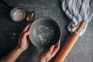 a person holding a bowl of food next to a wooden spoon