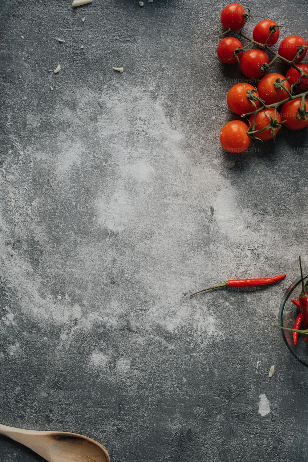 uma mesa coberta com uma tigela de tomates e uma colher de pau