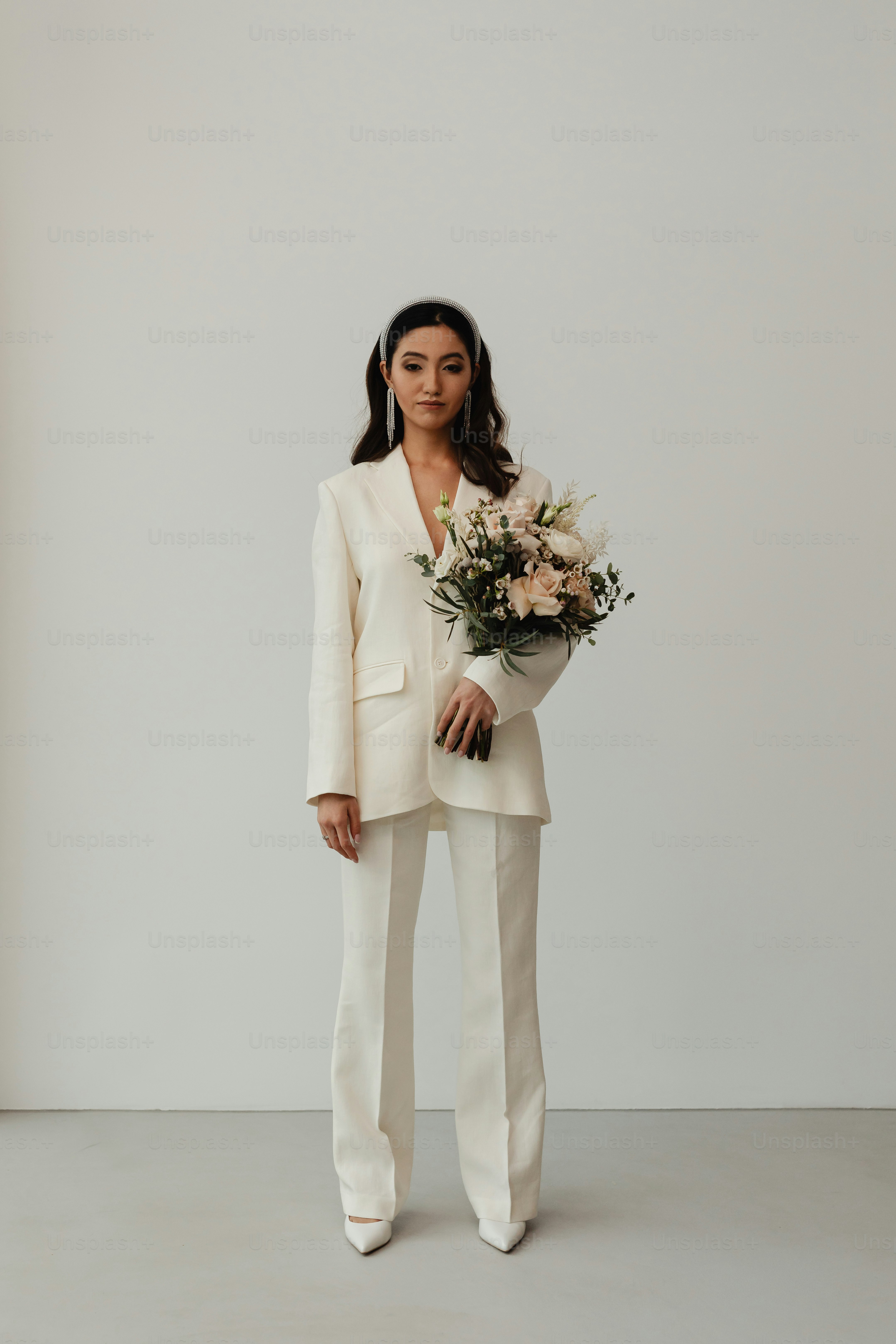 a woman in a white suit holding a bouquet of flowers