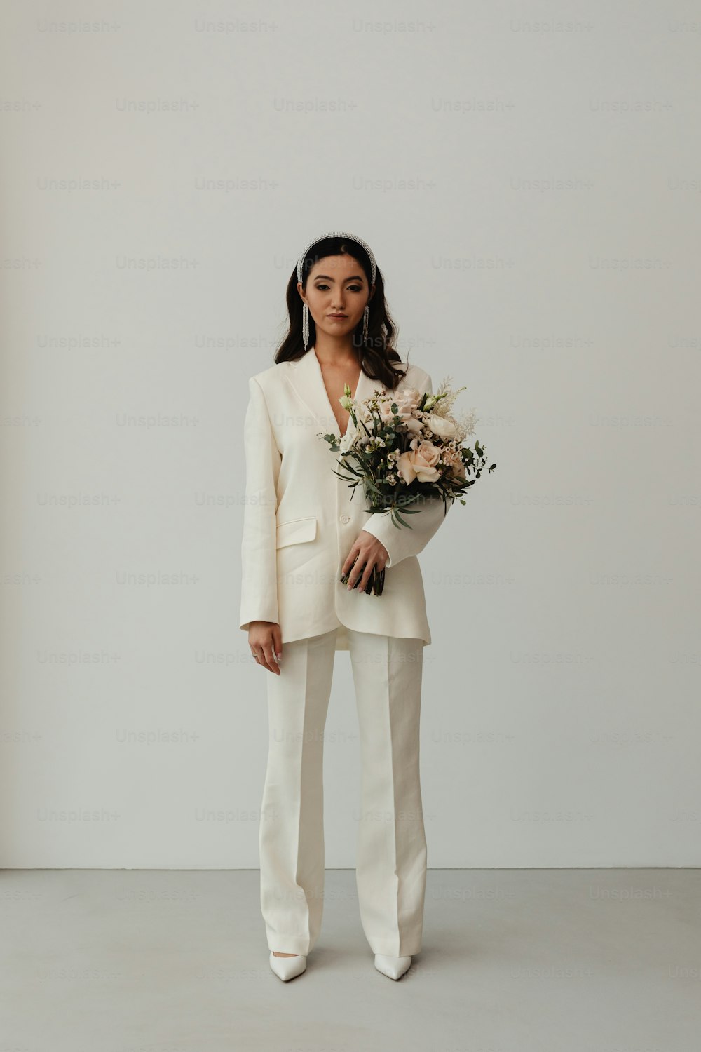 a woman in a white suit holding a bouquet of flowers