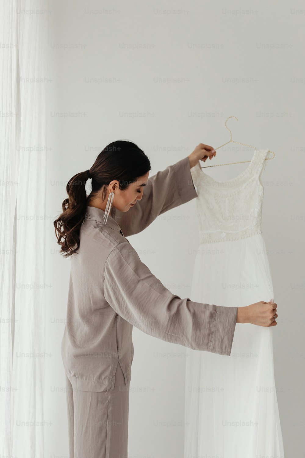 a woman standing next to a dress on a hanger