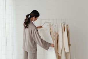 a woman standing in front of a rack of clothes