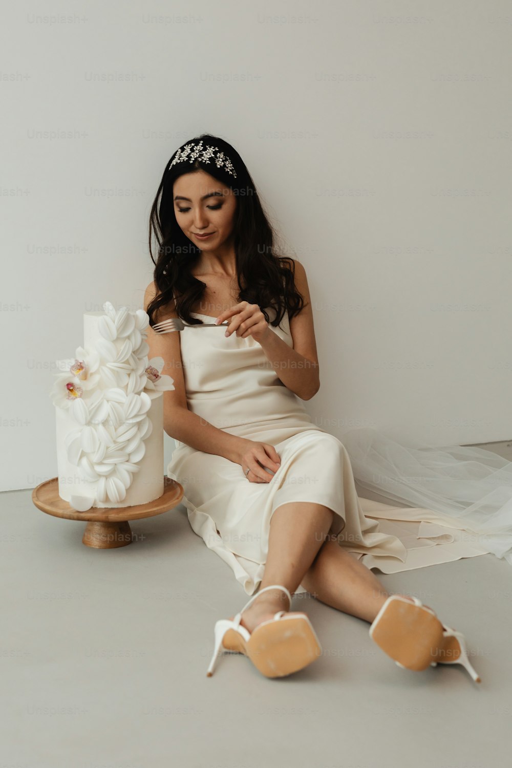 Eine Frau im weißen Kleid sitzt neben einem Kuchen