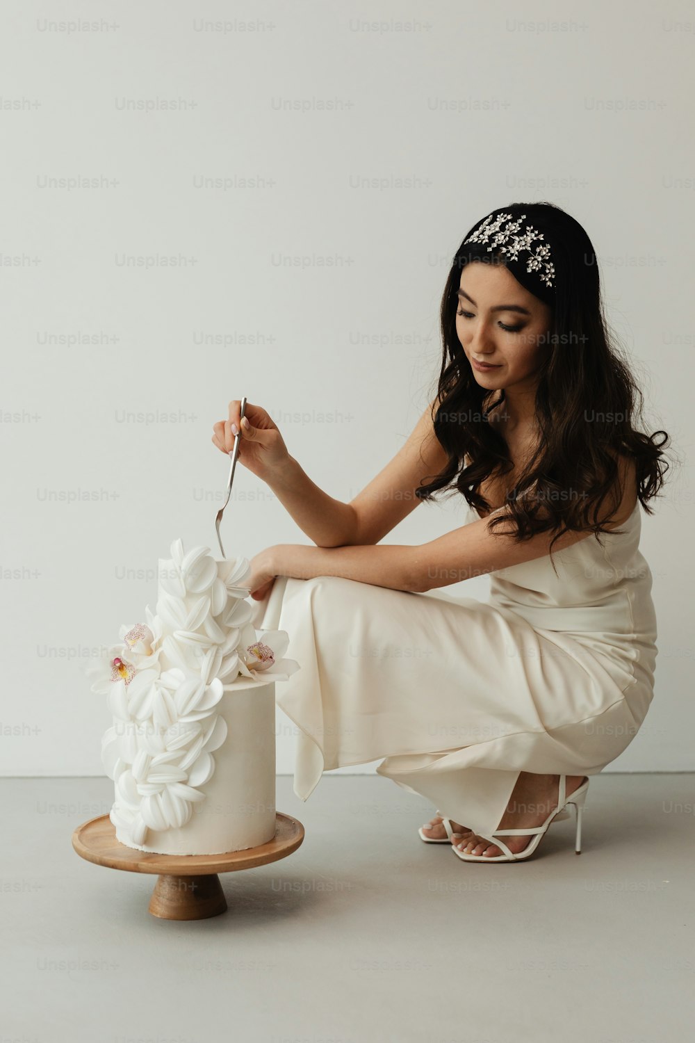 Eine Frau in einem weißen Kleid schneidet eine Hochzeitstorte an