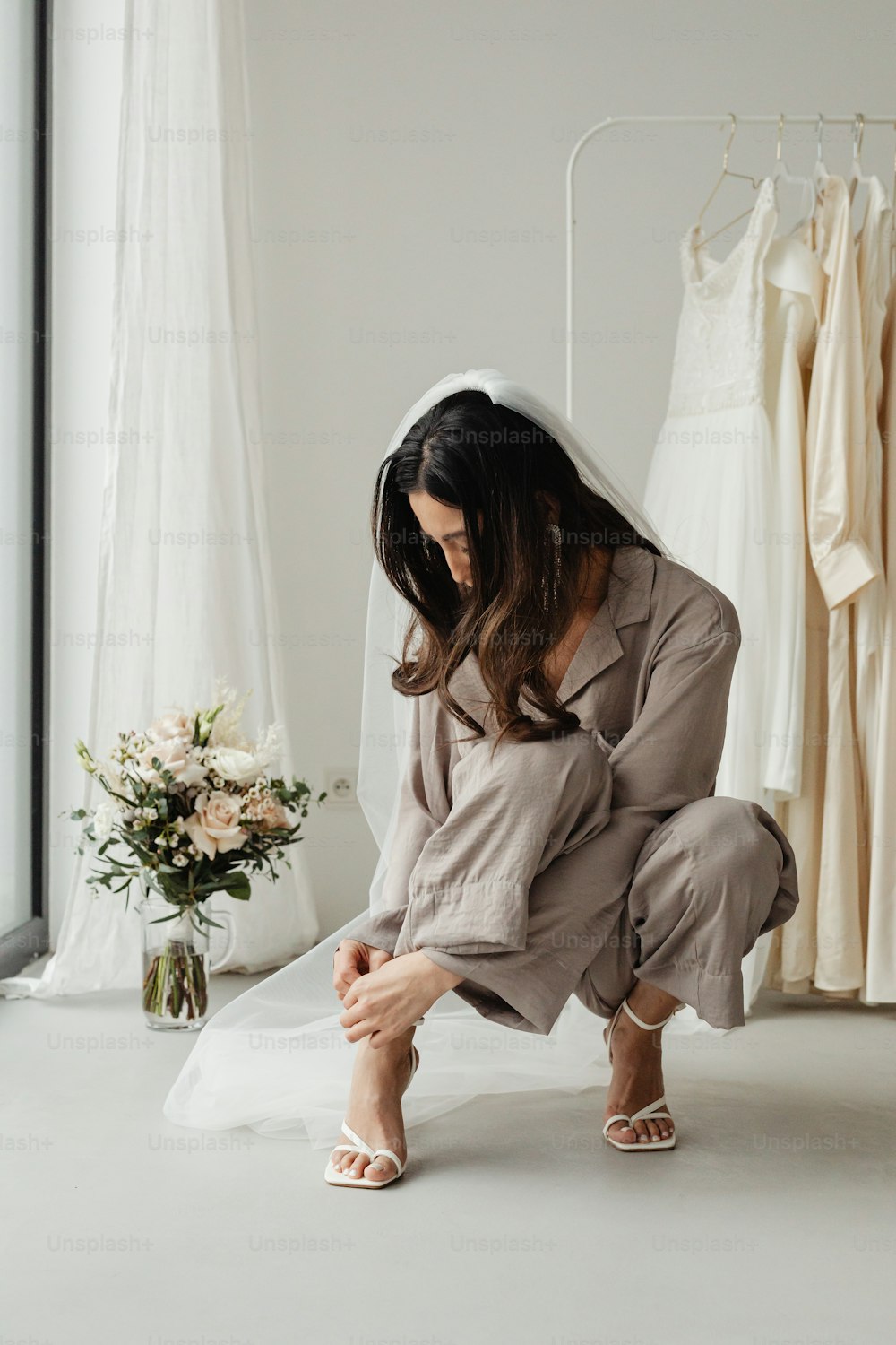 a woman kneeling down in front of a wedding dress