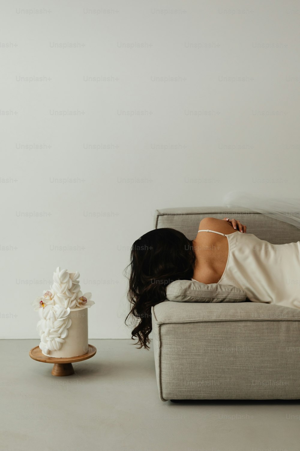 a woman laying on a couch next to a cake