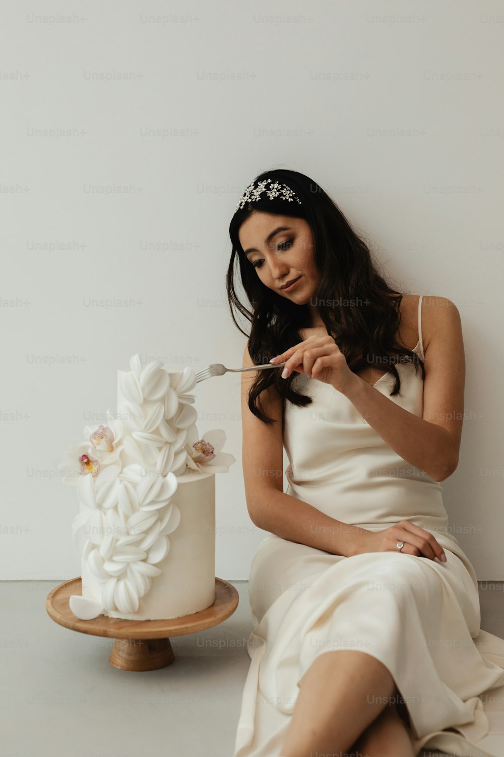 a woman in a white dress sitting next to a cake