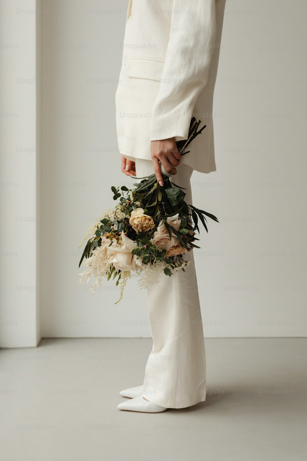 uma pessoa em um terno branco segurando um buquê de flores