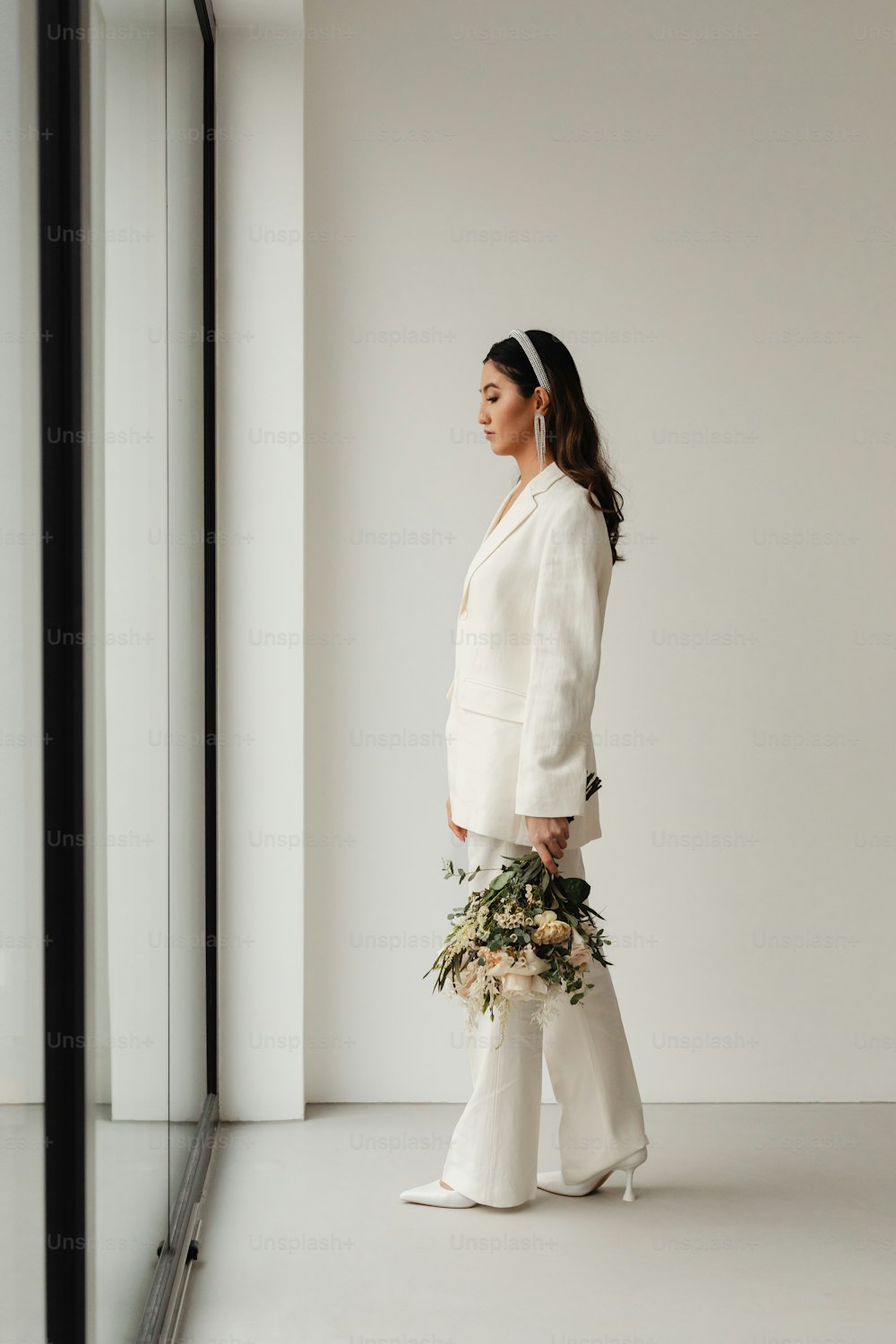 a woman in a white suit and flower bouquet