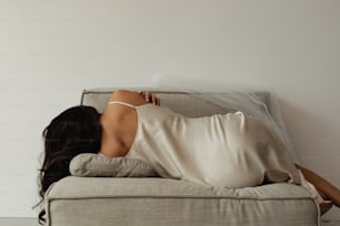 uma mulher em um vestido branco deitado em um sofá