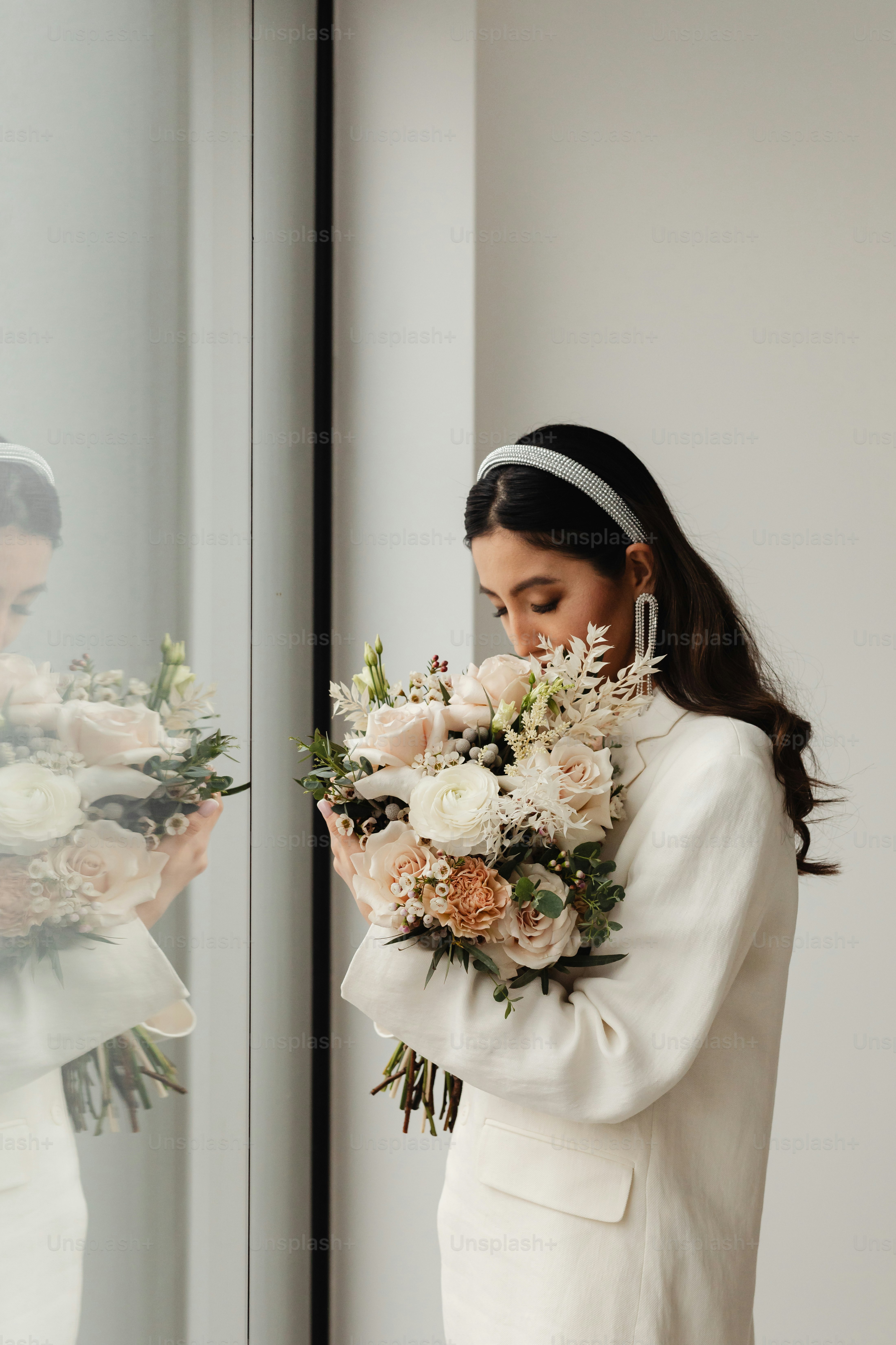 a woman in a white suit holding a bouquet of flowers
