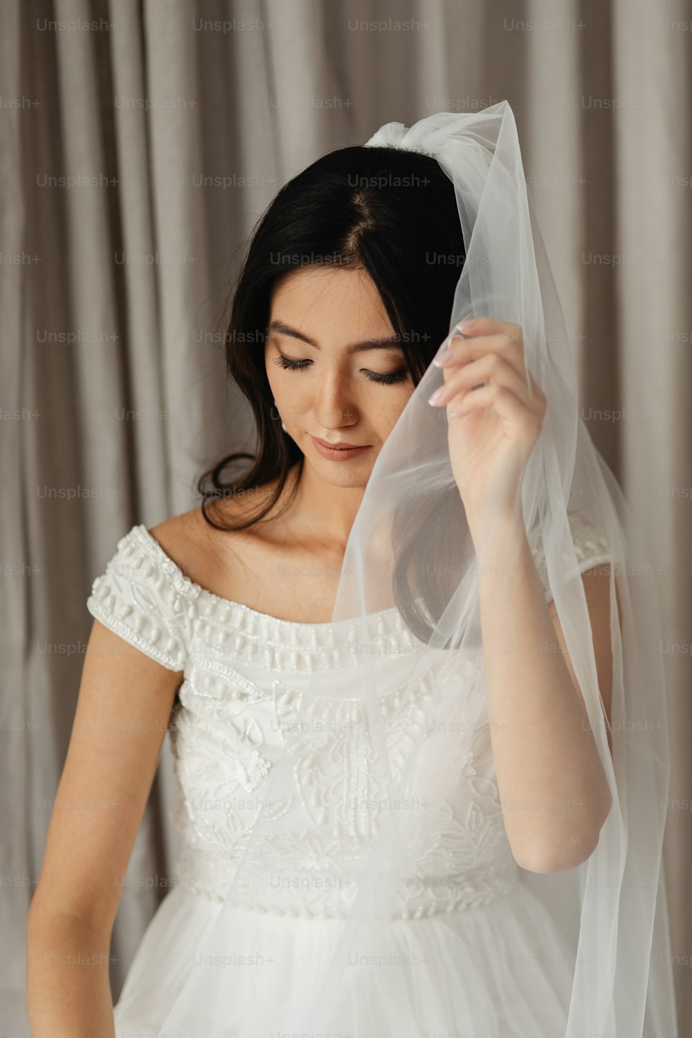 uma mulher em um vestido branco está segurando um véu