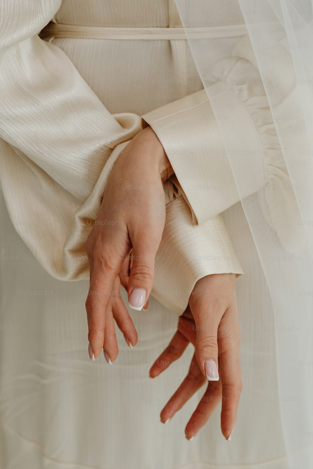 un primo piano delle mani di una persona che indossa un abito da sposa