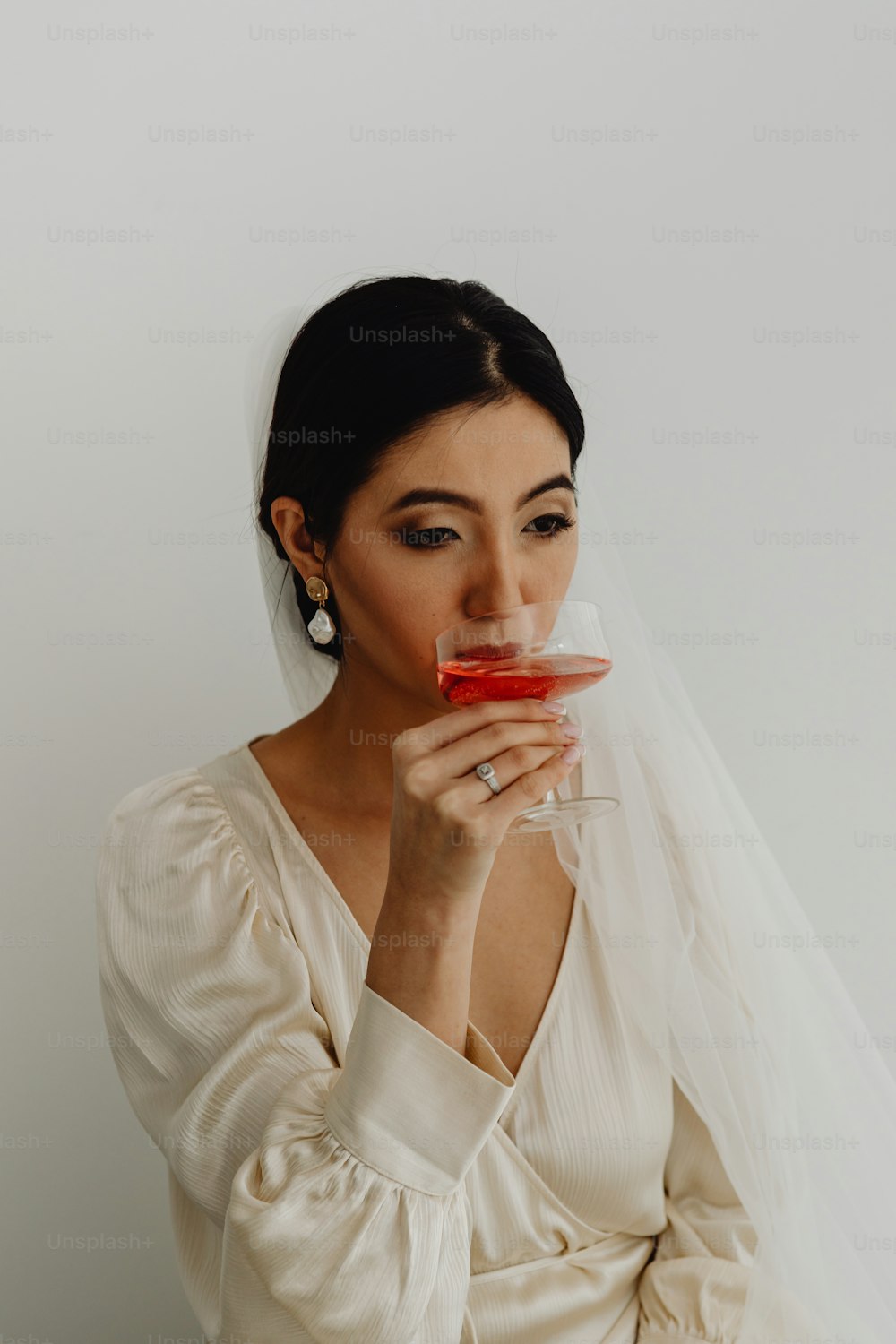 Eine Frau im Brautkleid hält ein Glas Wein in der Hand